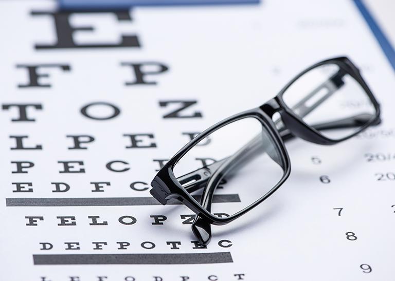 okulary leżące na tablicy do badania wzroku